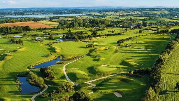 A golf course with multiple water bodies, winding paths, and a distant view of a town. - The Wiltshire Hotel, Golf and Leisure Resort (Swindon)