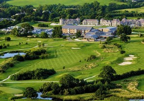 Um campo de golfe com um clube e edifícios residenciais ao fundo.