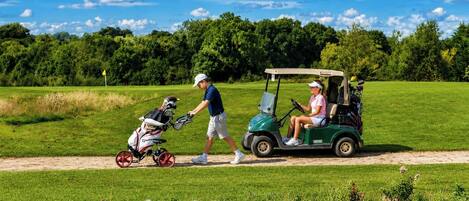 A golf course with a golf cart and a golf bag.