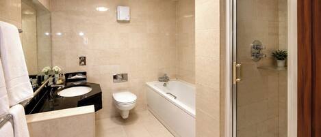 A modern bathroom with a bathtub, toilet, and shower.