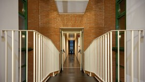 A long, narrow hallway with a brick wall on one side and a white railing on the other. - Hotel San Marco (Lucca)