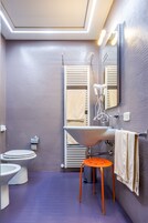 Un bagno moderno con un lavandino capiente, due servizi igienici, un portasciugamani e uno specchio.