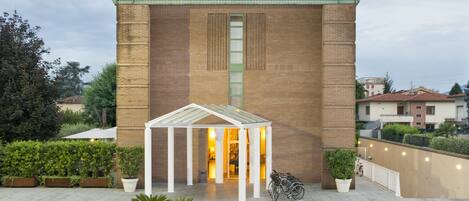 A building with a brick facade, a covered entrance, and potted plants.
