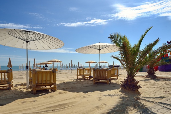 Een privéstrand, ligstoelen aan het strand, parasols, beachvolleybal