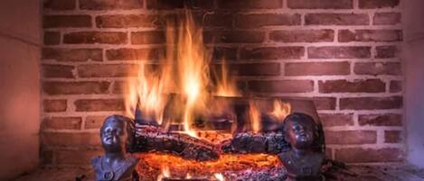 A fireplace with a brick wall background and two decorative busts on either side.