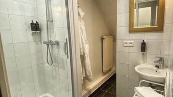 Un bagno moderno con doccia vetrata, lavandino bianco e uno specchio con cornice in legno.