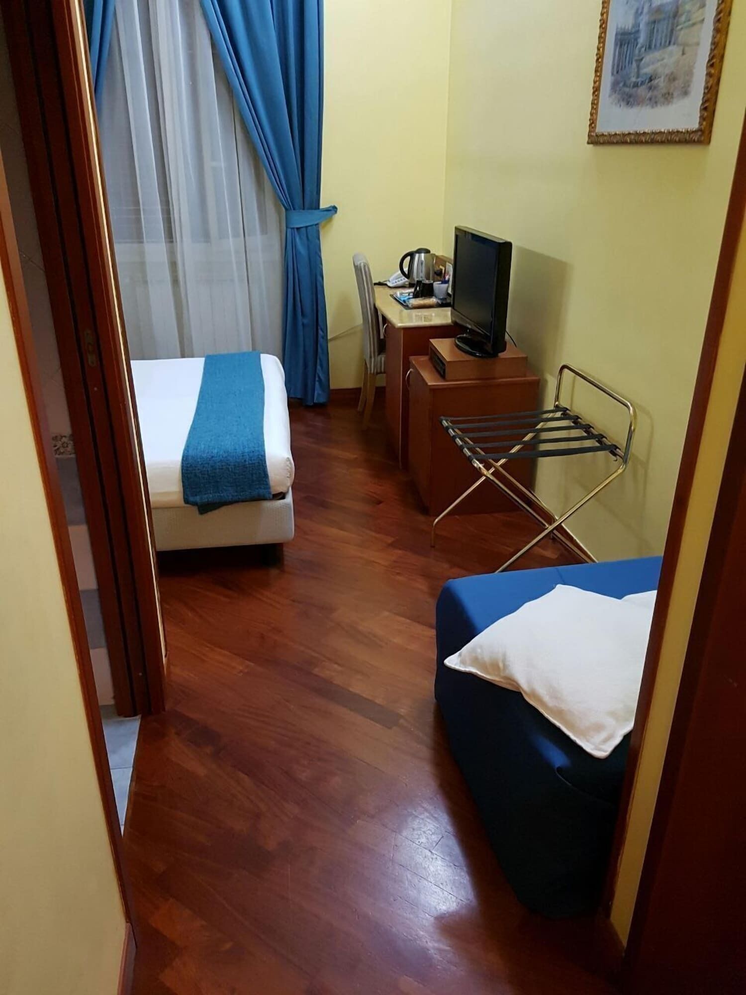 A compact room with a bed, a small desk with a television, and a seating area.