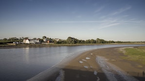 A riverbank with a sandy beach, a row of houses, and a clear sky. - Shard Riverside Hotel, Bar & Restaurant (Poulton-le-Fylde)