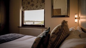 A hotel room with a bed, a window with a view of a bridge, a wall-mounted mirror, and a nightlight. - Shard Riverside Hotel, Bar & Restaurant (Poulton-le-Fylde)