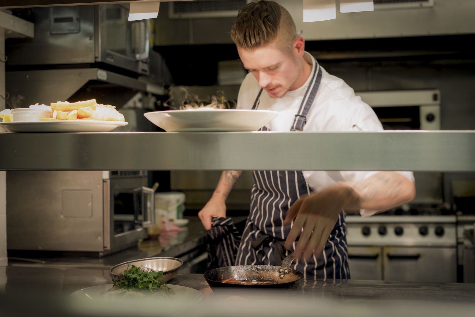A chef in a professional kitchen with stainless steel appliances and a clean, organized workspace.