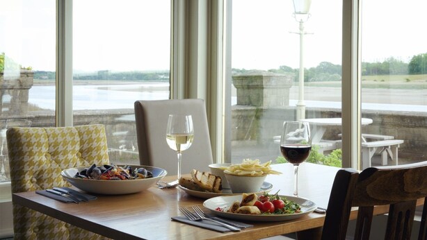 A dining table with a bowl of mussels, a plate of fries, a glass of white wine, and a glass of red wine. - Shard Riverside Hotel, Bar & Restaurant (Poulton-le-Fylde)