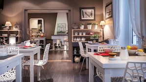 A modern dining area with white furniture, a central island, and various decorative items. - Hôtel des Alpes (Annecy)