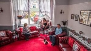 Een woonkamer met rode leren banken, een hangstoel en een rood tapijt.