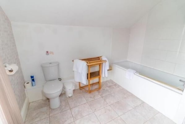 A bathroom with a toilet, bidet, and a wooden shelf with towels. - Quorn Lodge Hotel (Melton Mowbray)