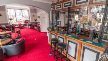 A bar area with a red carpet, bar stools, and a counter with a mirror.