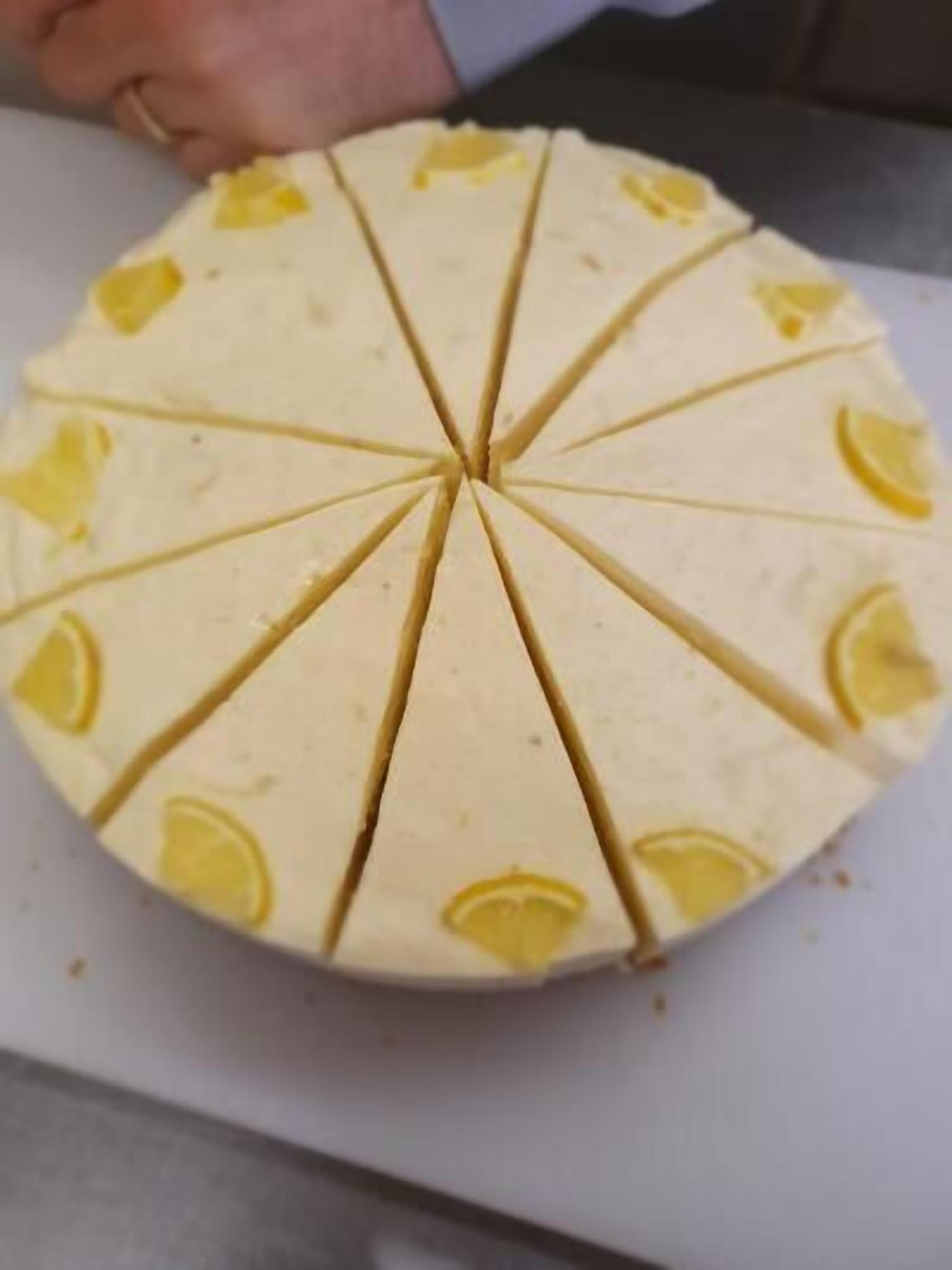 A round cake with lemon slices on top, cut into eight equal pieces.