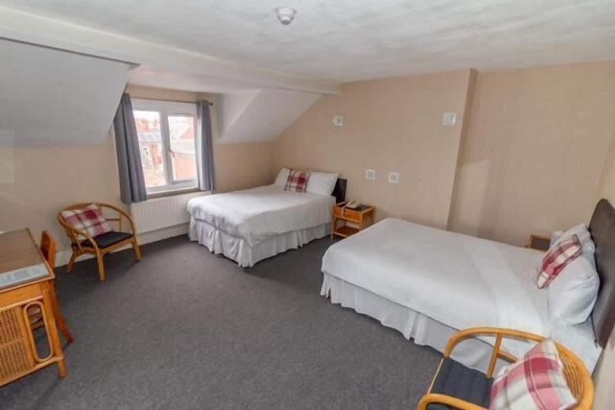 Une chambre avec deux lits, un bureau et une chaise.