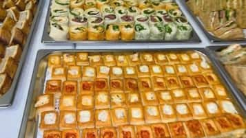 Ein Buffet mit verschiedenen Speisen, darunter Sandwiches, Gebäck und weitere Backwaren.