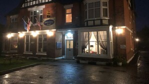 Een traditioneel hotel in Tudor-stijl met een opvallend erker en een bord met de tekst Quorn Lodge Hotel.