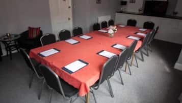 Una sala de conferències amb una taula llarga coberta amb un mantell vermell, i cadires al voltant.