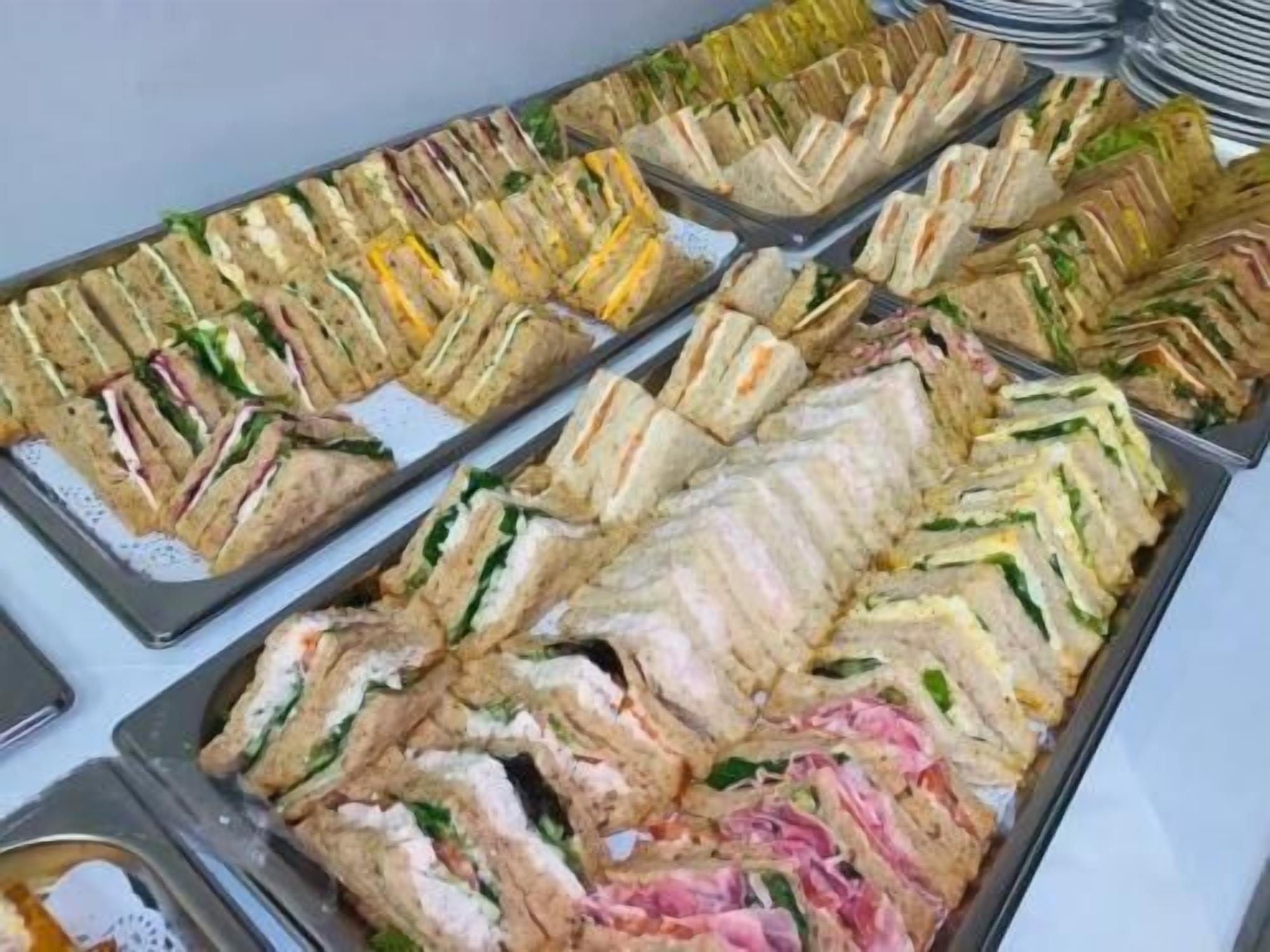 A buffet with various sandwiches arranged on trays.