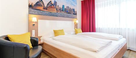 A hotel room with a bed, a sofa, and a painting of a city skyline.