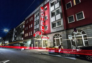 Un hotel con un llamativo letrero rojo, varias ventanas y una bicicleta estacionada afuera.