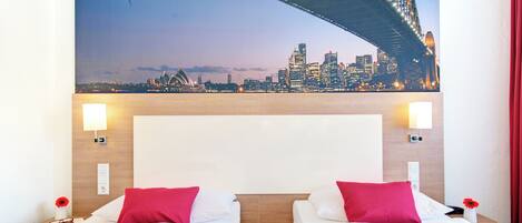 Habitación de hotel con dos camas, vista al horizonte de la ciudad y un amplio ventanal con vistas al Puente de Sydney.