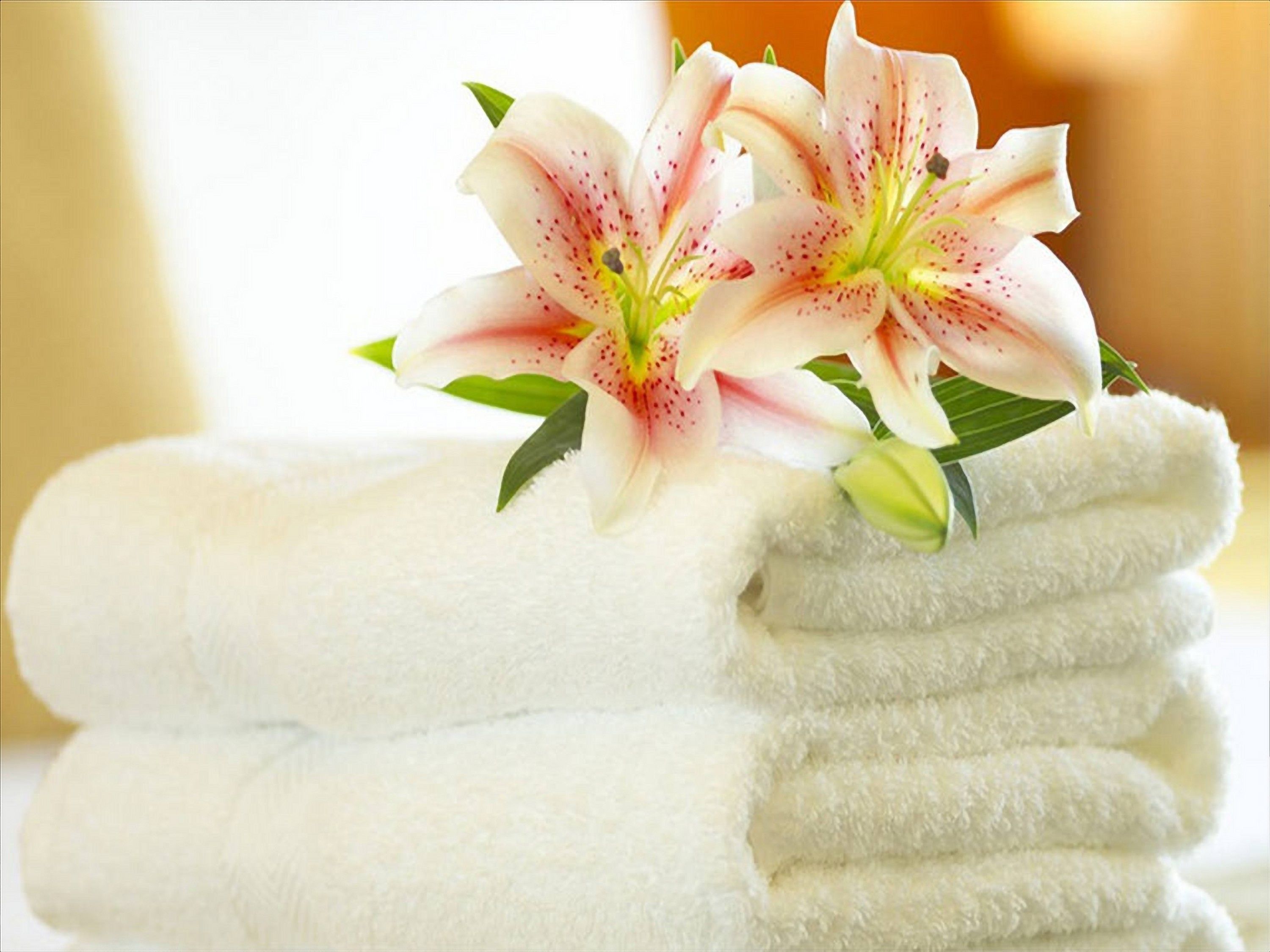 Un mucchio di asciugamani bianchi con un giglio rosa e bianco sopra.