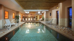 An indoor swimming pool with tiled flooring, lounge chairs, and a stone wall mural. - Chalet des Neiges - Oz en Oisans (Oz)