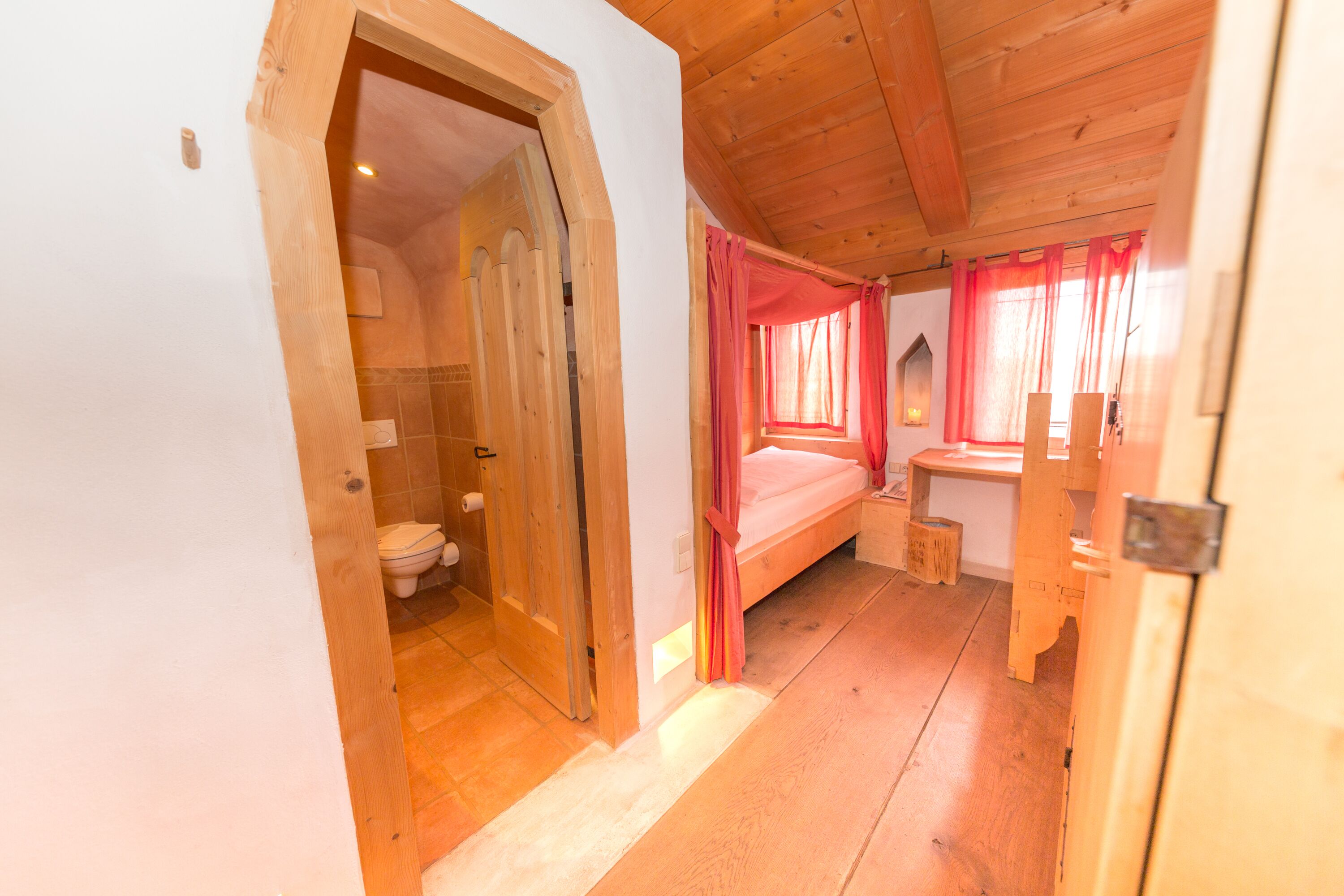 Ein Holzinterieur mit einem hölzernen Bett, einem kleinen Holztisch und einer Holzbank.