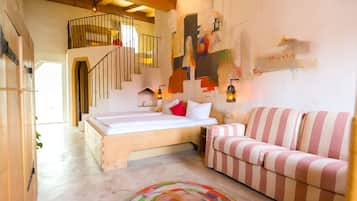Un dormitorio con una cama, un sofá a rayas, una escalera y un cuadro en la pared.