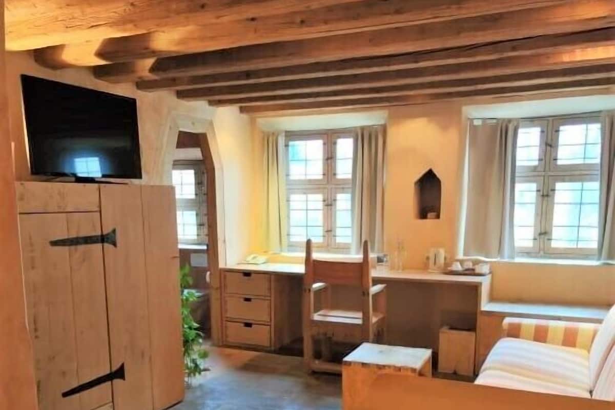 A cozy room with a bed, a desk, and a TV.