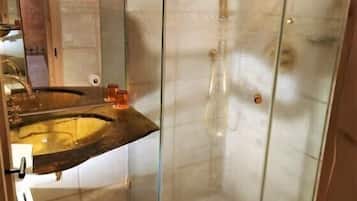 A modern bathroom with a glass shower enclosure, a sink with a marble countertop, and a toilet.