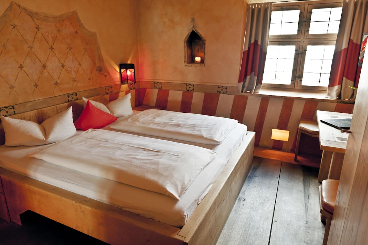 A room with two beds, a small table, and a window with curtains.