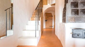 A modern interior with a staircase, white walls, and a stone fireplace.