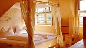 A wooden room with a bed, a small table, and a window with curtains. - Hotel San Gabriele (Rosenheim)