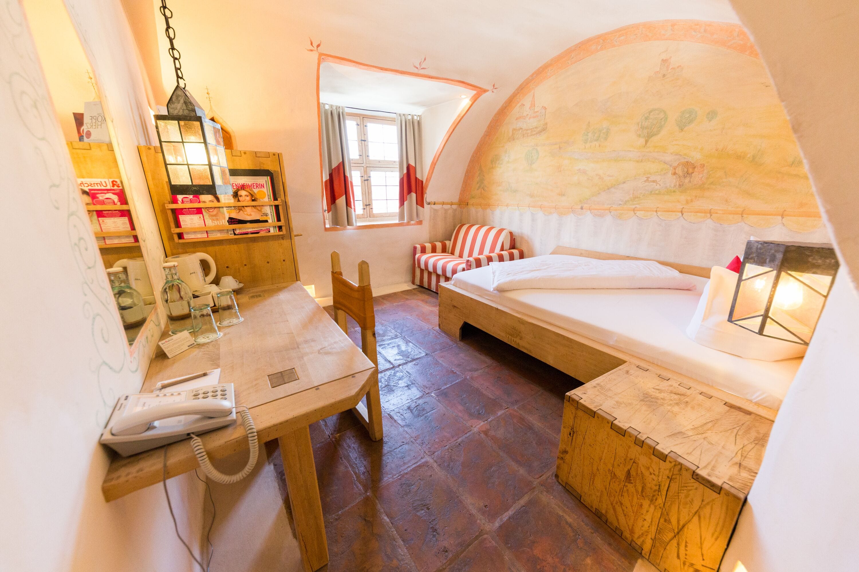 Une pièce confortable avec un bureau en bois, un lit et une fenêtre avec des rideaux.