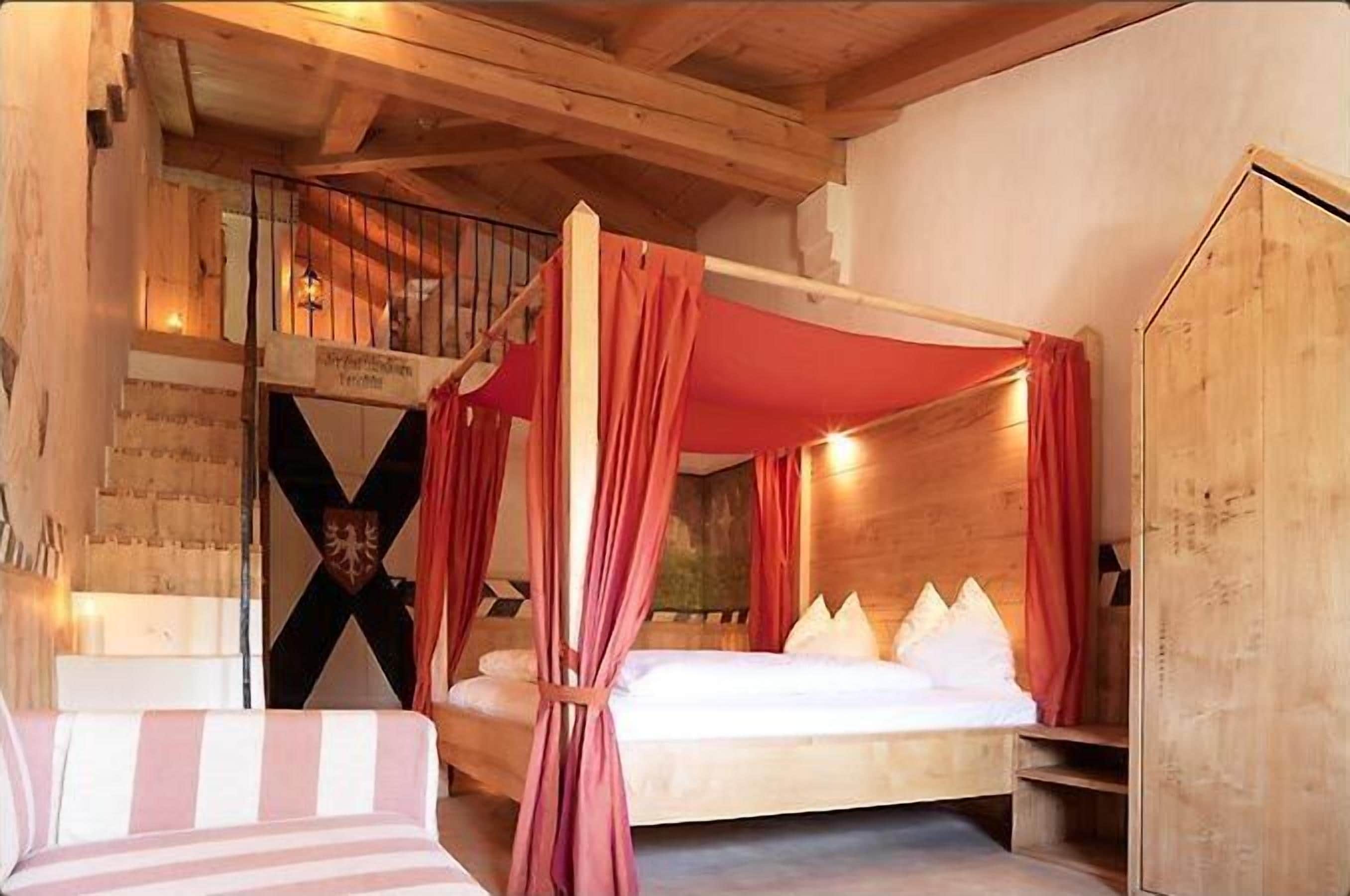 A wooden cabin bedroom with a bed, a canopy, and a staircase.