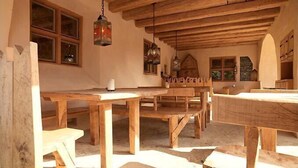 A rustic wooden dining area with benches and tables, wooden beams on the ceiling, and hanging lanterns. - Hotel San Gabriele (Rosenheim)