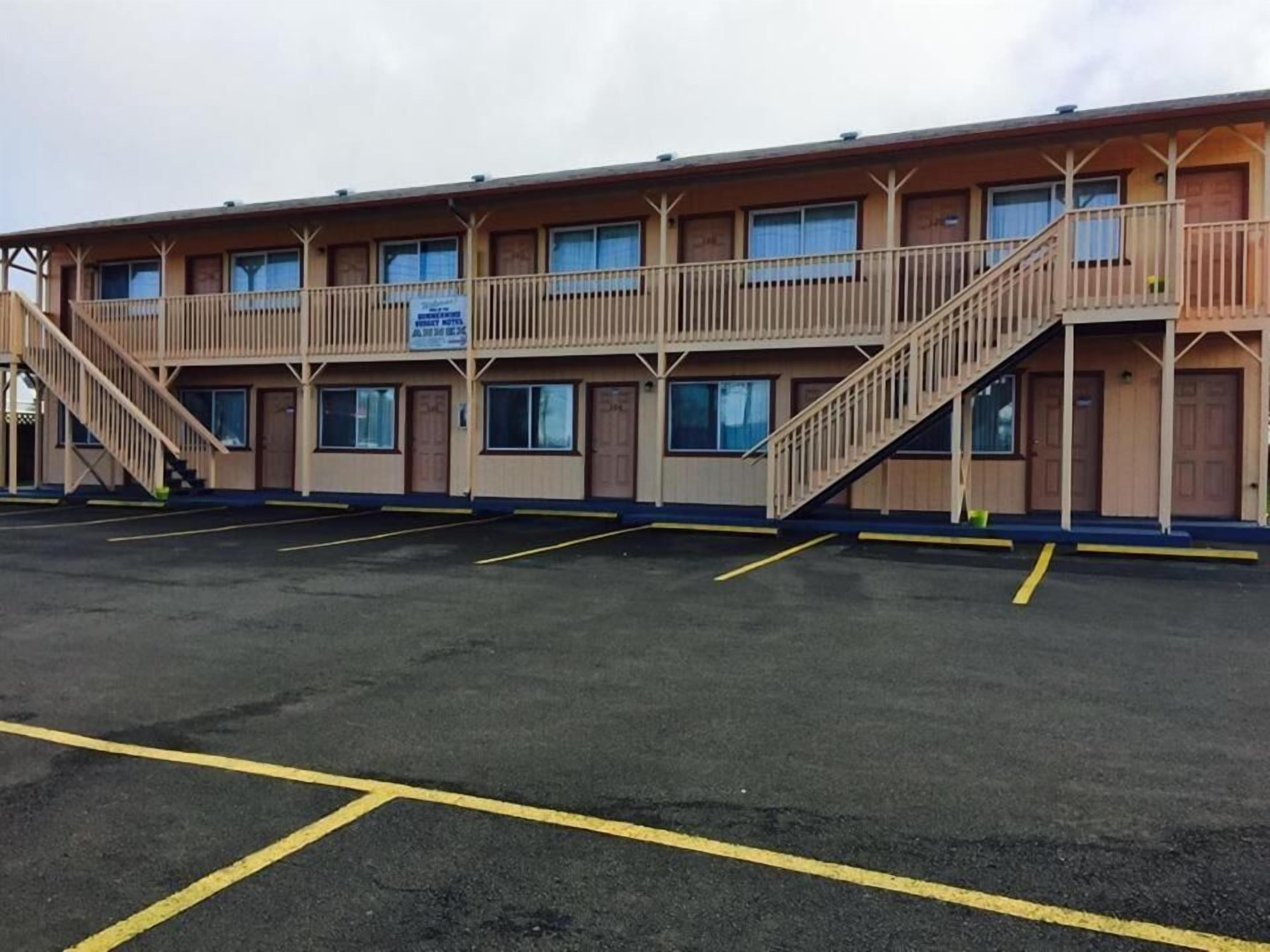 A motel with a two-story structure, a parking lot, and a staircase leading to the upper level.