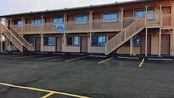 A motel with a two-story structure, a parking lot, and a staircase leading to the upper level.