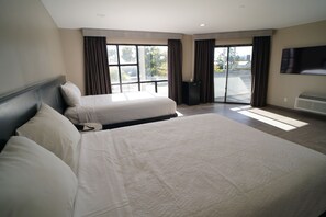 A hotel room with two beds, a flat-screen TV, a large window, and a sliding door to an outdoor area. - Gardena Terrace Inn (Gardena)