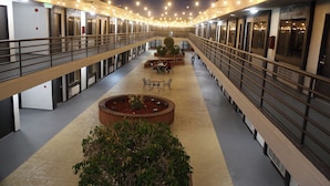 A hotel corridor with a central seating area, multiple doors, and a railing along the upper level. - Gardena Terrace Inn (Gardena)