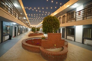 Amplio espacio interior con un macetero central de ladrillo, varias ventanas y un techo decorado con luces colgantes.