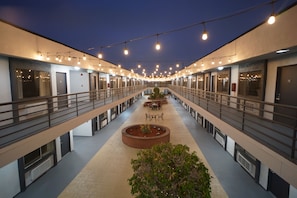 A multi-level hotel corridor with a central walkway, railings, and a seating area with tables and chairs. - Gardena Terrace Inn (Gardena)