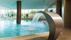 Ein Innenpool mit Wasserfall, großen Fenstern und modernem Design.