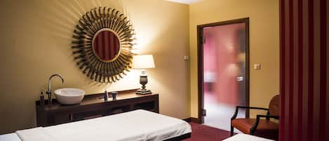 Habitación de hotel con dos camas, un espejo grande, un lavamanos y una silla.
