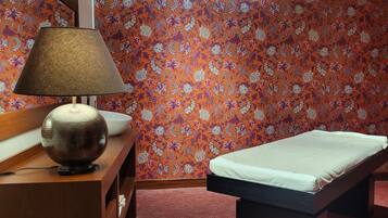 Une chambre avec un lit, une table de chevet avec une lampe et un mur décoré d’un motif.