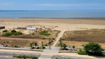 Une plage avec une promenade en bord de mer, un petit bâtiment avec une enseigne et une vue dégagée sur la mer.